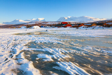 Abisko in Lapponia in Svezia. Tramonto al lago di Tornetrask ghiacciato. Sole, neve, ghiaccio, al circolo polare artico, un paesaggio del nord Europa - obrazy, fototapety, plakaty