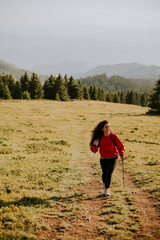 Young woman walking with backpack over green hills