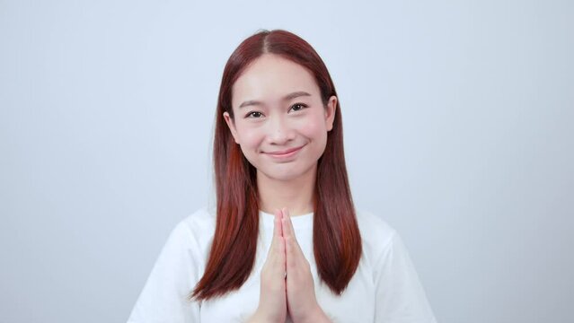 A happy, hopeful Asian woman in a black suit bows politely and greets a customer.