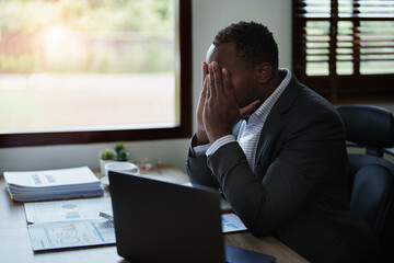 Burnout American African business man in stress works with many paperwork document, migraine attack, Freelance, work from home