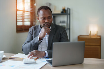 Obraz premium middle aged man American African using computer laptop with planning working on financial document, tax, exchange, accounting and Financial advisor. auditor or audit concepts