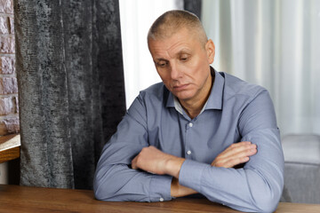 Portrait of a pensive middle-aged man sitting at a table.