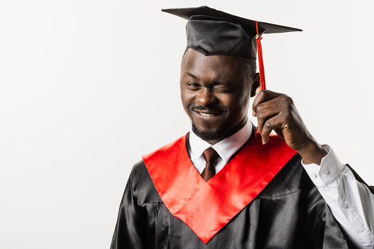 Portrait of graduate african man graduated from university and got master degree. Graduation. Happy african man in black graduation robe is smiling on white background.