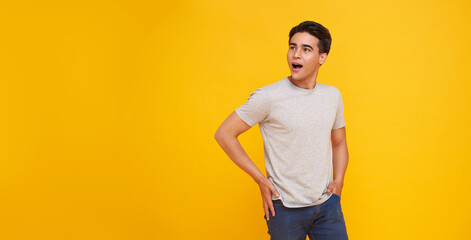 Surprised and Shocked asian man covering mouth isolated on yellow studio background. copy space