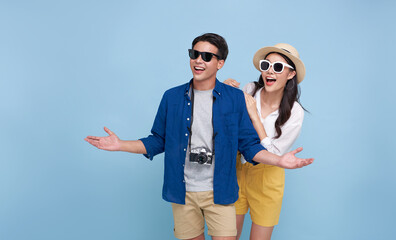 Happy smiling Asian couple tourist traveler standing hugging and looking copy space isolated on blue background. Vacation time