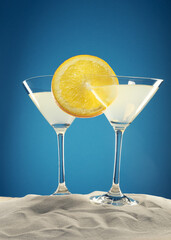 cocktail with orange slice on white sand