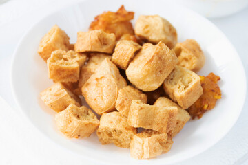 Deep fried tofu on white plate with peanut sweet and sour dipping sauce.
