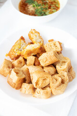 Deep fried tofu on white plate with peanut sweet and sour dipping sauce.