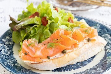 Smoked salmon with cream cheese on french baguette and fresh salad.