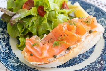 Smoked salmon with cream cheese on french baguette and fresh salad.