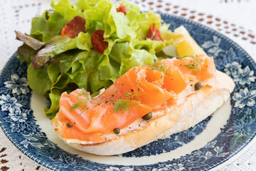 Smoked salmon with cream cheese on french baguette and fresh salad.