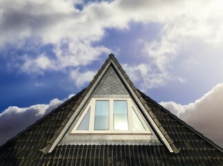 Open roof window in velux style with black roof tiles.