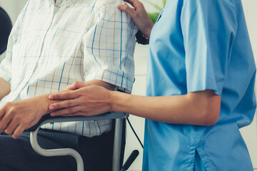 Happy positive asian nurse giving support and touching contented senior man with love. Nursing home for the elderly, elderly health and illness, senior patient carer.