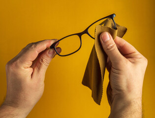 Close-up of a person's hands wiping dust off glasses with a napkin