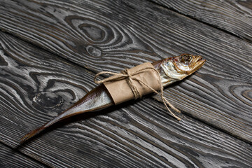 Putassu Cold smoked. The fish is wrapped with a strip of paper. Tied with linen twine. Lies on pine boards. Close-up.