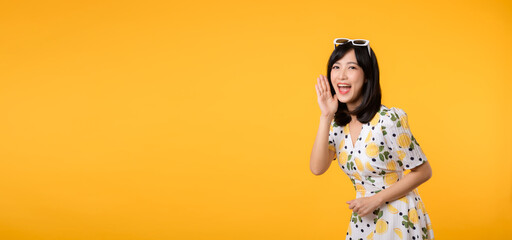 Portrait cheerful happy attractive asian young woman announcing shout message in copy space isolated on yellow background. Promotion advertising or news communication concept.