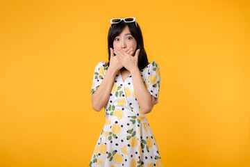 Portrait asian young woman hushing with hand sign shares secret makes taboo gesture wears casual springtime dress isolated on yellow background. Shh be quiet concept