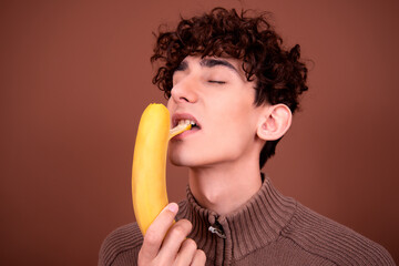Young man with a banana on a brown background.