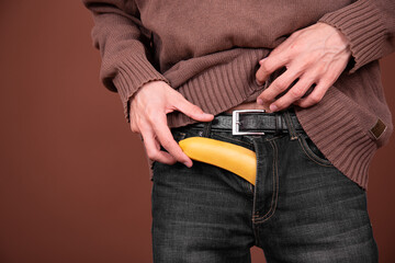 Young man with a banana on a brown background.
