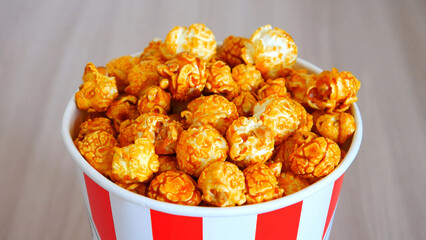 Close-up of beautiful caramel popcorn in a cardboard cup on a wooden table