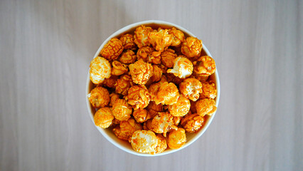 Top view of beautiful caramel popcorn in a cardboard cup on a wooden table