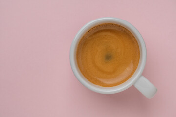 White porcelain espresso coffee cup over pink background, top view, copy space, closeup. Hot coffee...