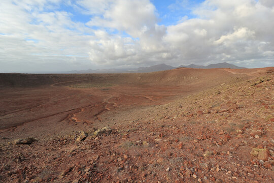 Amazing photo of Red Mountain's volcanic crater, captured with an ultra-wide angle lens, featuring shrubs in the center and rocks in the foreground, in Lanzarote, Canary Islands