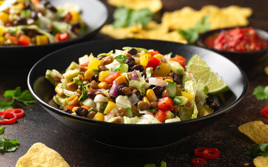 Mexican style salad of black beans, lentils, corn, tomato and lettuce with a salsa and tortilla chips