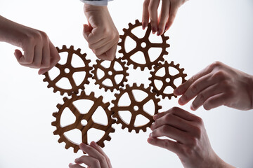 Hand holding wooden gear by businesspeople wearing suit for harmony synergy in office workplace...