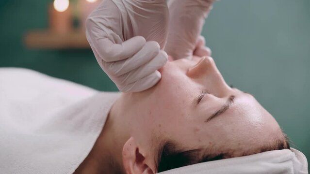 Cosmetologist makes a buccal massage of the patient's facial muscles in spa. Close up.