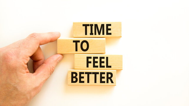 Time to feel better symbol. Concept words Time to feel better on wooden block. Beautiful white table white background. Businessman hand. Motivational business time to feel better concept. Copy space