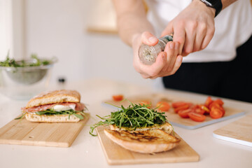 Man using pepper grinder for preparing tasty sandwich at home. Middle selection 