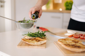 Man pouring cold pressed linseed oil on classic Italian bruschetta. Vegan healthy food