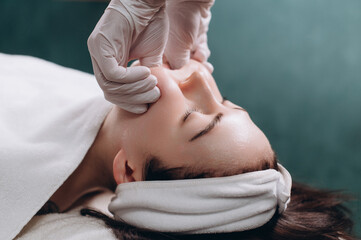 Cosmetologist makes a buccal massage of the patient's facial muscles in spa. Close up.
