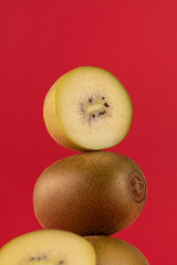 Still life of balancing golden kiwis on a red background. The concept of fruits