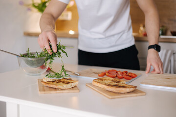 Close-up of man put organic arugula on bruschetta. Vegan food