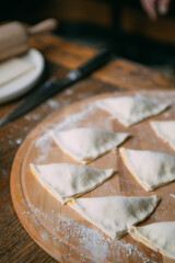 Men's hands make triangular pies with stuffing. Close-up. The cook cooks pies from the dough.