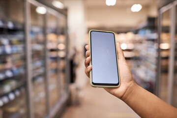 Close up of female hand holding smartphone with white screen mockup in supermarket interior