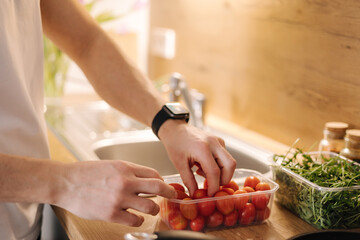 Close-up of human hand take red cherry tomatoes in the kitchen