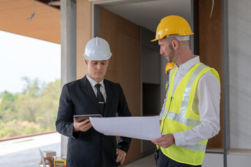 Architect and engineer work together with a sketch of the building and discussing it at the construction site.