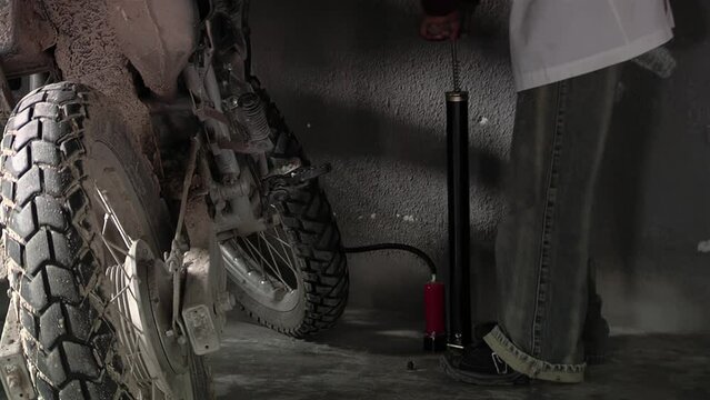 Inflating Motorcycle Tyre, Man Pumping Air to Motorcycle Tyre Using Manual Air-pump. Closeup.  