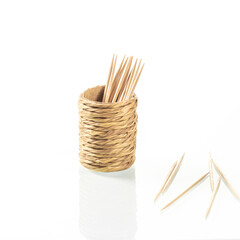 Cup made of straw for toothpicks with reflection in a white mirror background close-up