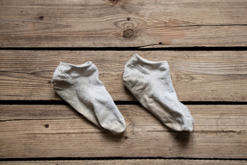 Fototapeta na wymiar Dirty short white socks lie on the wooden floor of the house