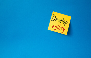 Develop agility symbol. Orange steaky note with concept words Develop Agility. Beautiful blue background. Business and Develop agility concept. Copy space