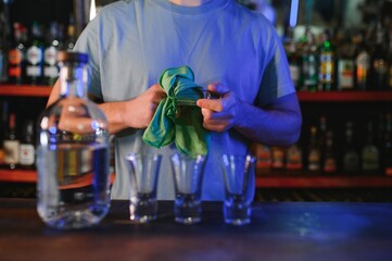 Barman pouring hard spirit into glasses in detail