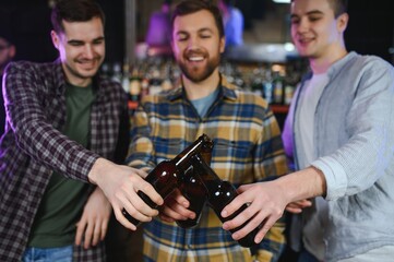 Old friends meeting. Happy young men in casual wear toasting with beer while sitting in beer pub together