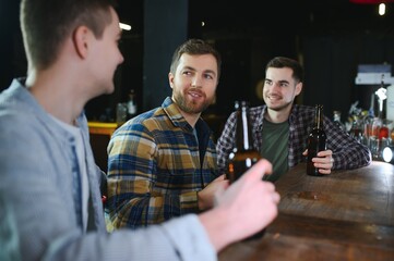 Friends resting in the pub with beer in hands. Having conversation.