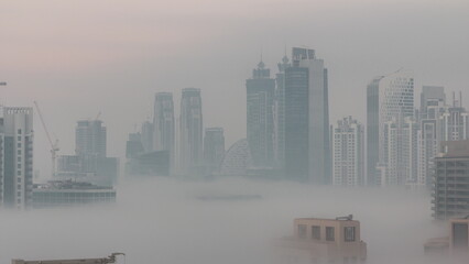 Dubai skyscrapers with morning fog in business bay district night to day timelapse.