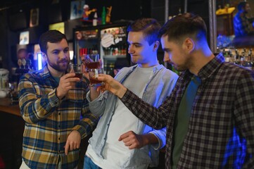 male friends spending time together in bar and having fun. Bearded men smiling, looking at each other and communicating. Men holding crystal glasses of whisky or scotch.