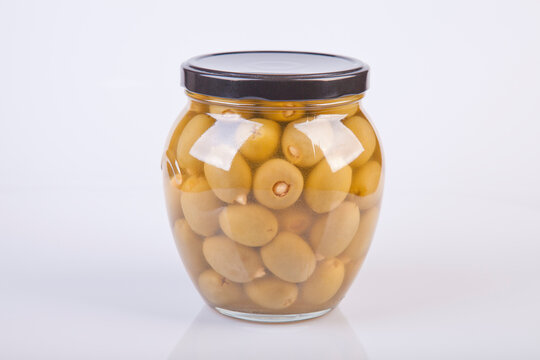 A Jar With Olive Oil And Some Green Olives Isolated Over A White